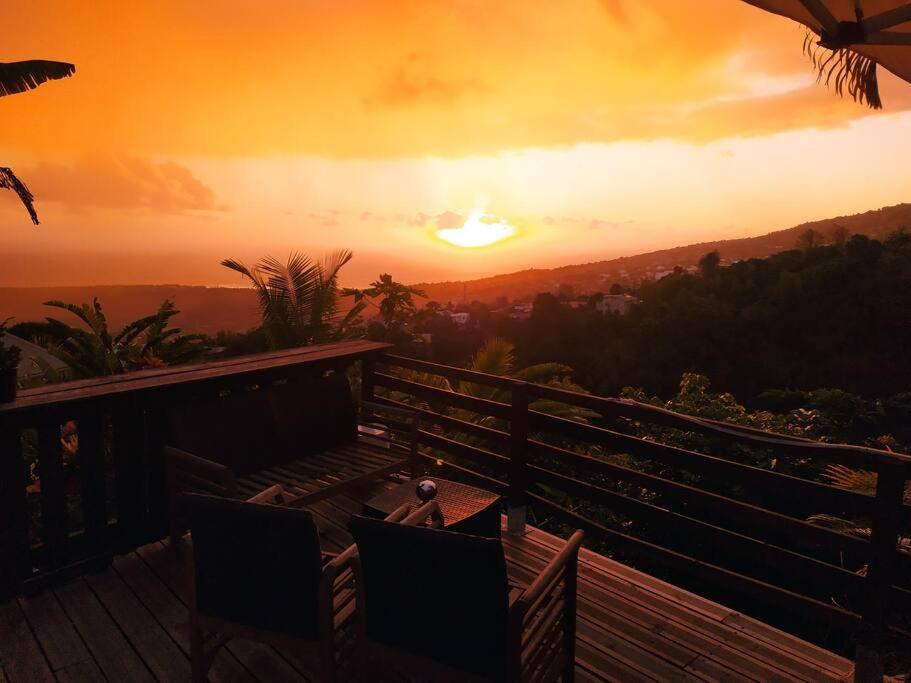 a sunset from a deck with a table and chairs at Ti Coin La Paix Airbn'beer in Étang-Salé