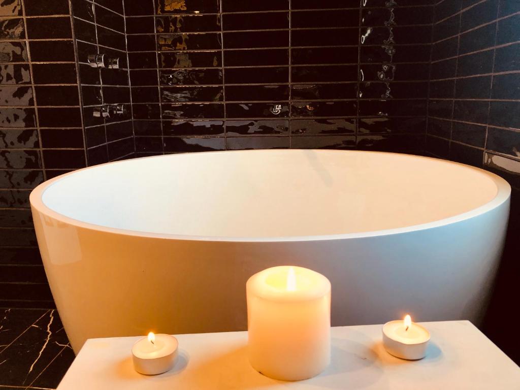 two candles sitting on a table in front of a bath tub at Beach Escape Studio Walk To The Beach in Rosebud