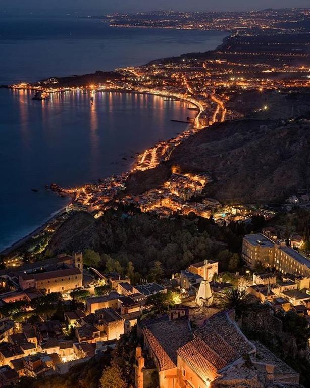 an aerial view of a city and the ocean at night at Sweet House Taormina in Taormina
