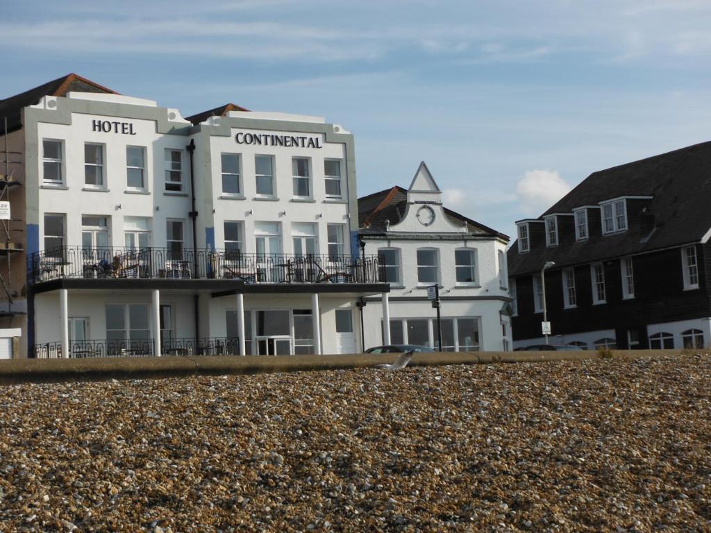 a white building on the beach next to buildings at Hotel Continental in Whitstable