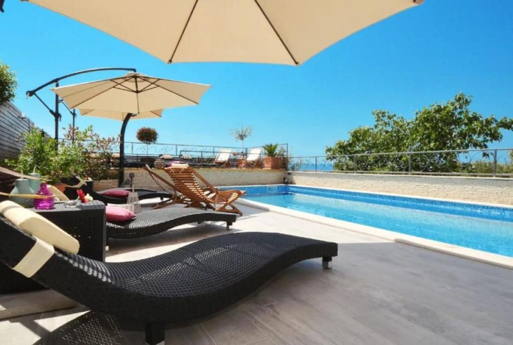 a patio with chairs and an umbrella and a pool at Apartments Villa Golden View in Trogir