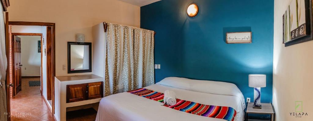 1 dormitorio con cama y pared azul en Casa Vista Magica, en Yelapa