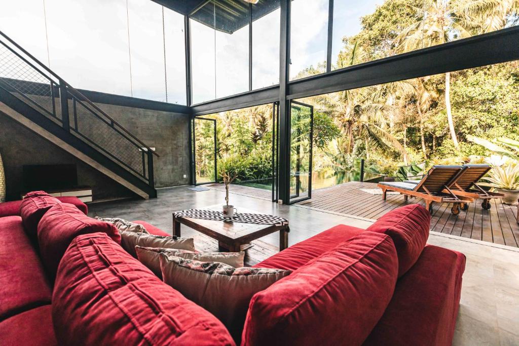 un salon avec un grand canapé rouge dans une maison dans l'établissement 3 Bedrooms Tropical Modernism Rice Field and Jungle, à Ubud