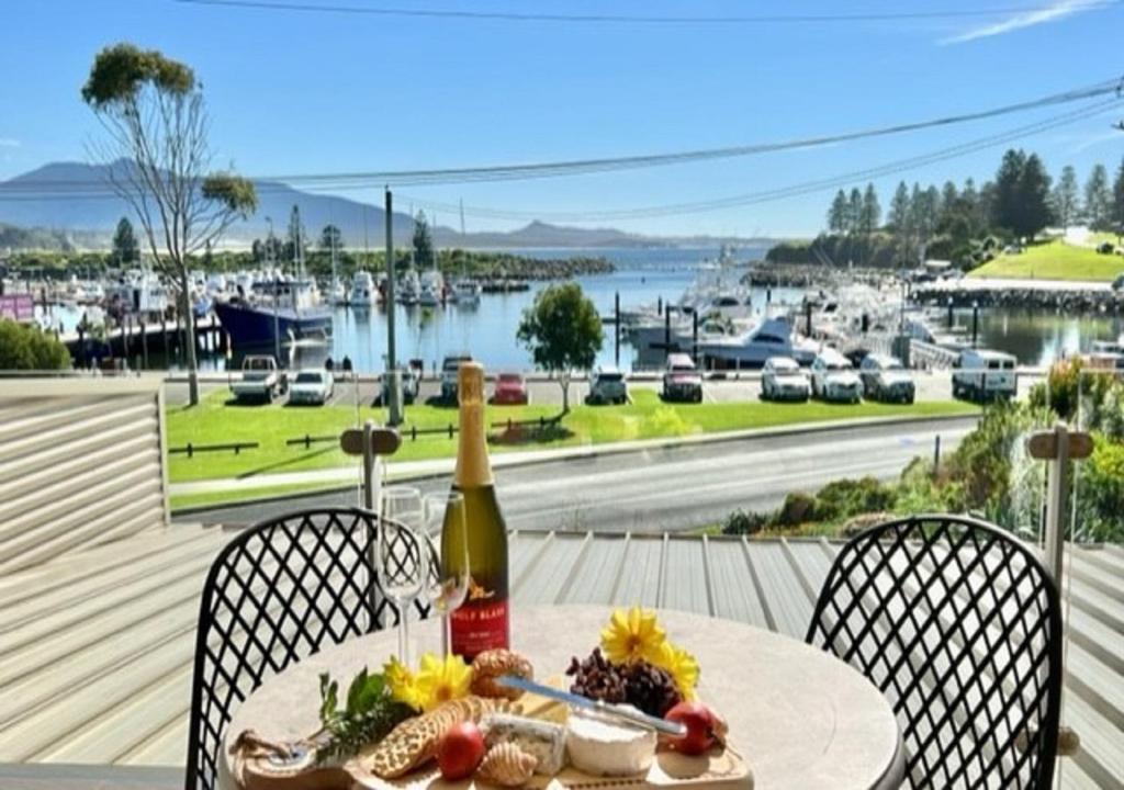 - une table avec une bouteille de vin et une assiette de nourriture dans l'établissement Vista Marina - 2 bedroom Apartment - Amazing views & location, à Bermagui
