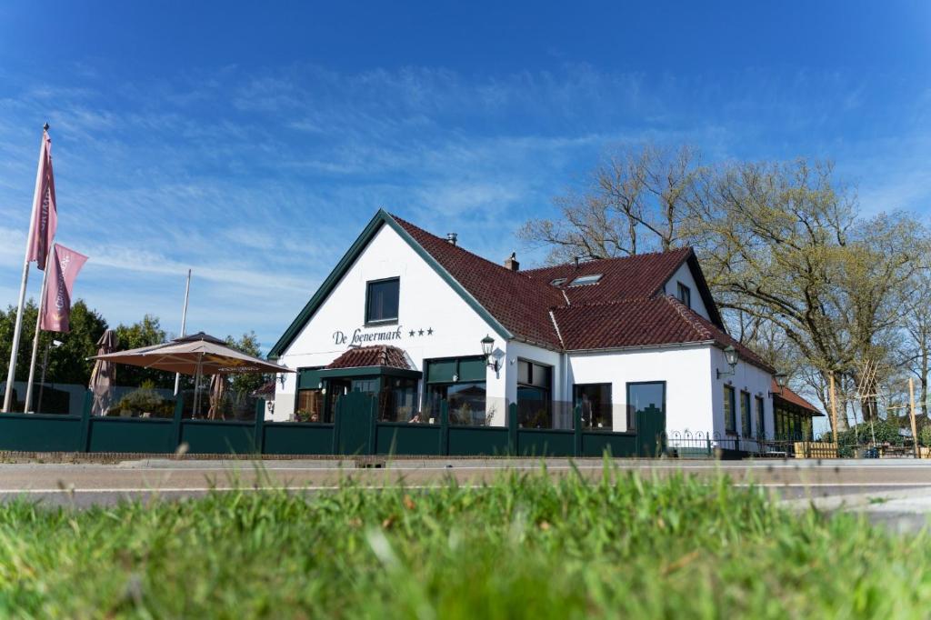 een wit gebouw met een rood dak op een straat bij Hotel Restaurant de Loenermark in Loenen