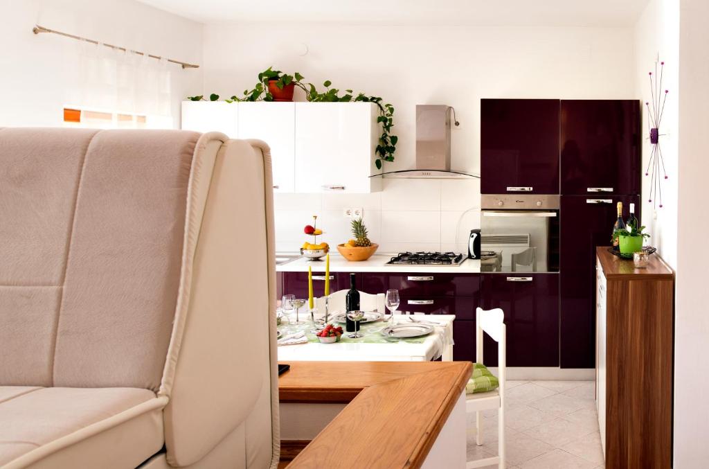 eine Küche mit weißen Schränken, einem Tisch und einem Stuhl in der Unterkunft Petar Pan in Šibenik