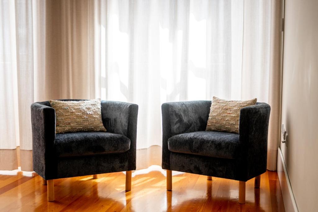 duas cadeiras sentadas em frente a uma janela em Mouzinho 129 - Carvalho no Porto