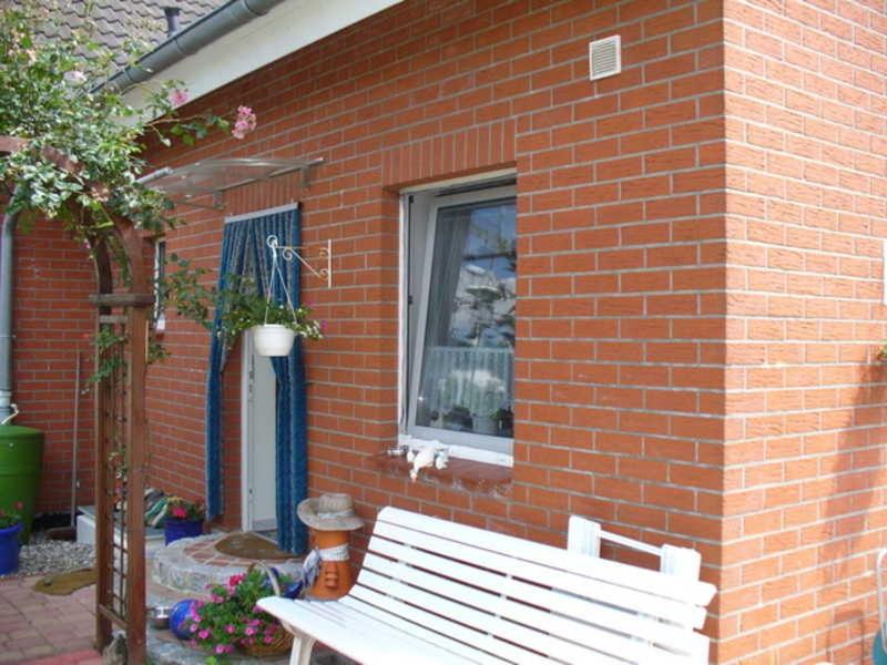 a white bench sitting in front of a brick building at Ferienwohnung Reins in Neustadt in Holstein