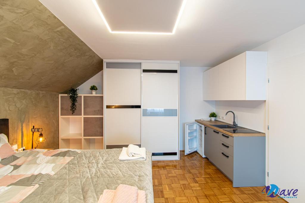 a bedroom with a bed and a kitchen with a sink at MODERN apartments WAVE near the AIRPORT in Velika Gorica