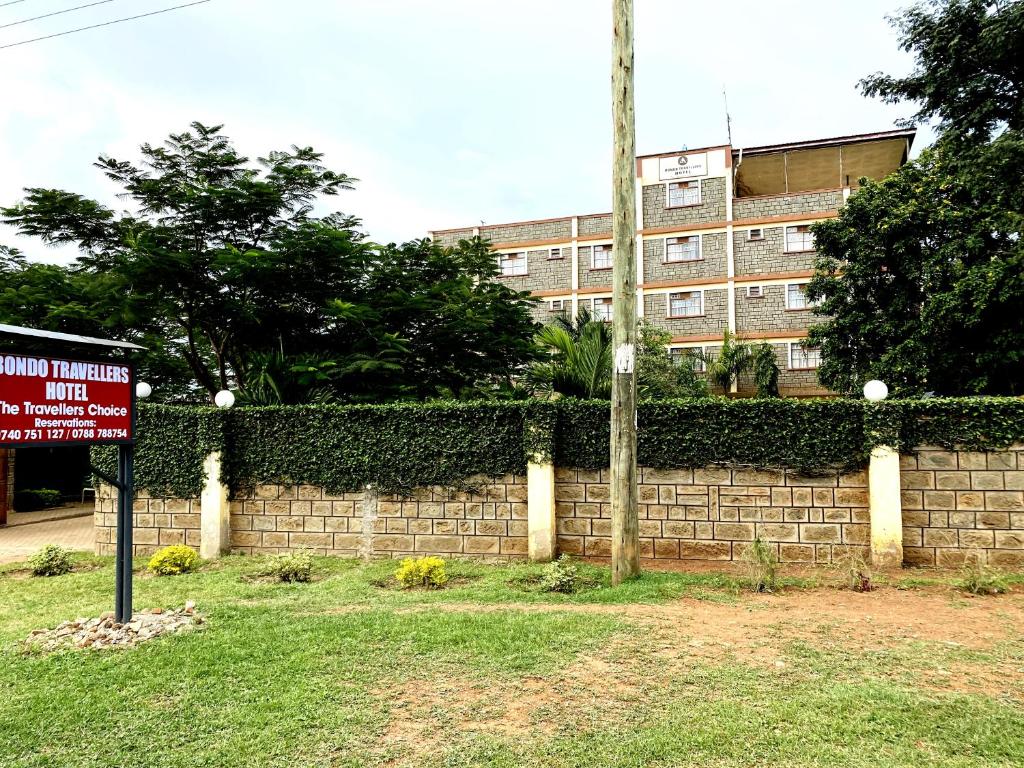 a brick wall with a sign in front of a building at Bondo Travellers Hotel in Bondo