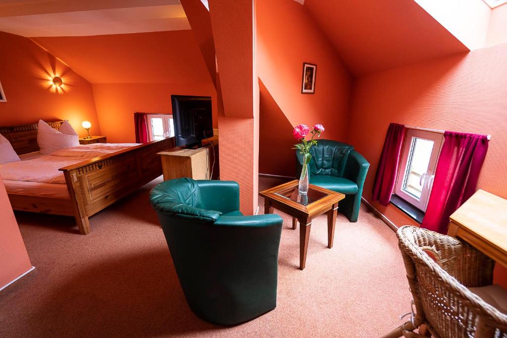 ein Hotelzimmer mit einem Bett und Stühlen sowie einem Schlafzimmer in der Unterkunft Pension am Dom in Schwerin