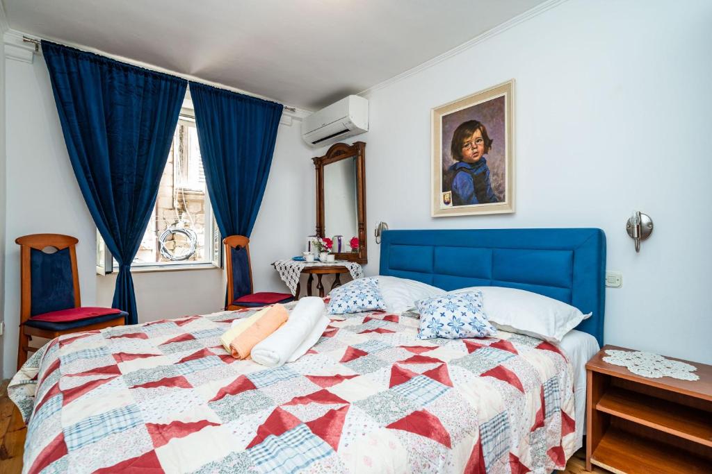 um quarto com uma cama azul com uma colcha vermelha e branca em Rooms Fausta Old Town em Dubrovnik