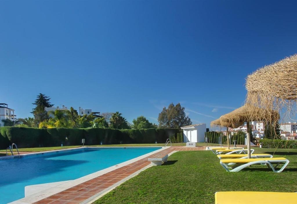 basen z krzesłami i parasolami w obiekcie Casa Eucalyptus Family Home w mieście Estepona