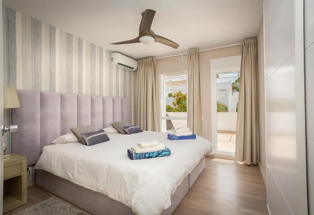 sypialnia z dużym białym łóżkiem i wentylatorem sufitowym w obiekcie Casa Eucalyptus Family Home w mieście Estepona