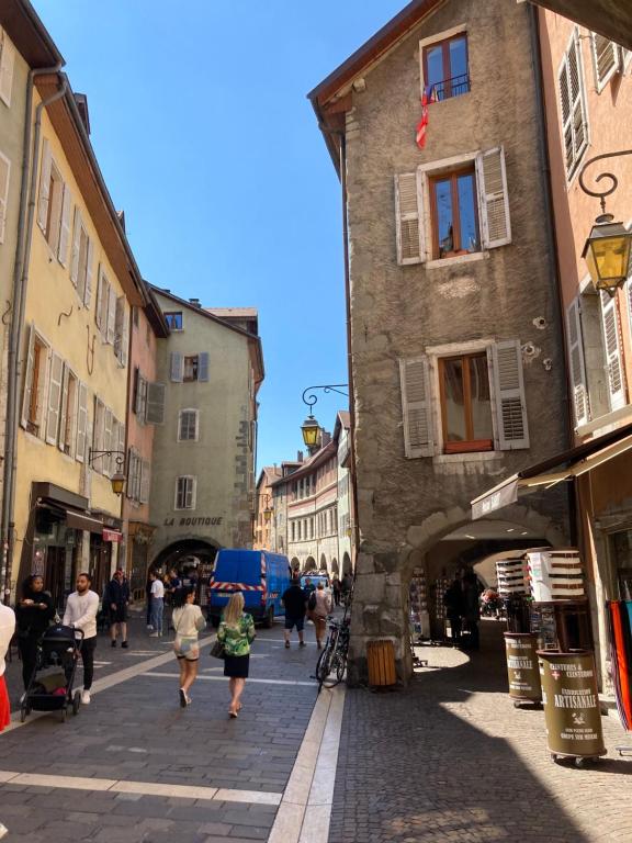 a group of people walking down a street with buildings at 2 Pieces cosy in Annecy