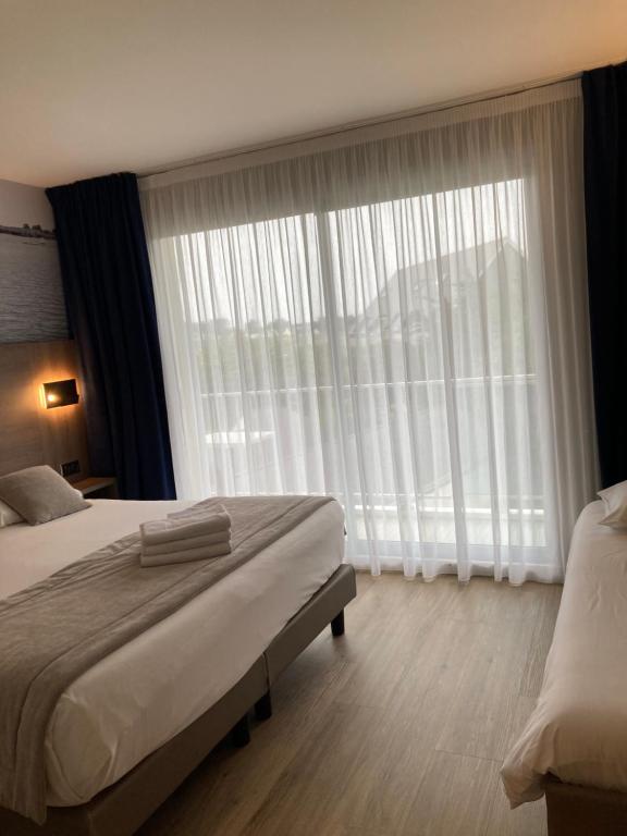 a bedroom with a bed and a large window at Hotel Europa in Quiberon