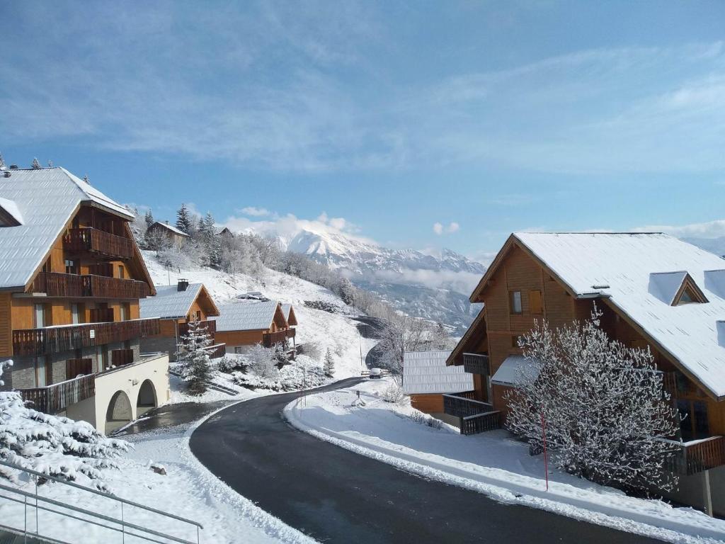 a snow covered road in a village with buildings at Location Pra-Loup Vacances à 1500 in Pra-Loup