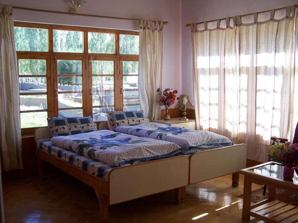a bedroom with two beds in a room with windows at Serdung Guest House in Leh