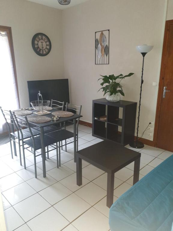 a dining room with a table and chairs and a clock at LE RELAX in Lurcy-Lévis