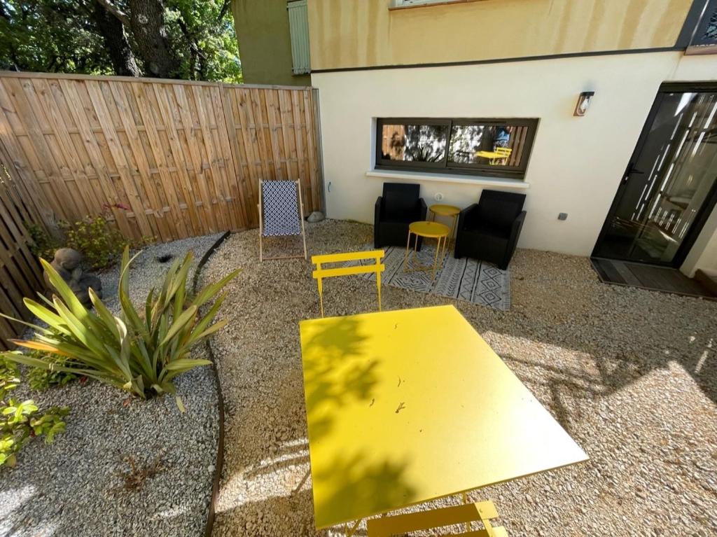 uma mesa amarela e cadeiras num quintal em Magnifique cocon sous les chênes em Saint-Martin-de-Londres