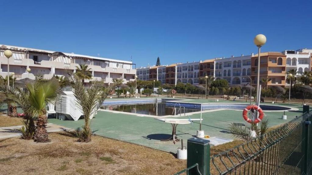 a tennis court with palm trees in front of buildings at Playa Vera 137 natura world in Vera