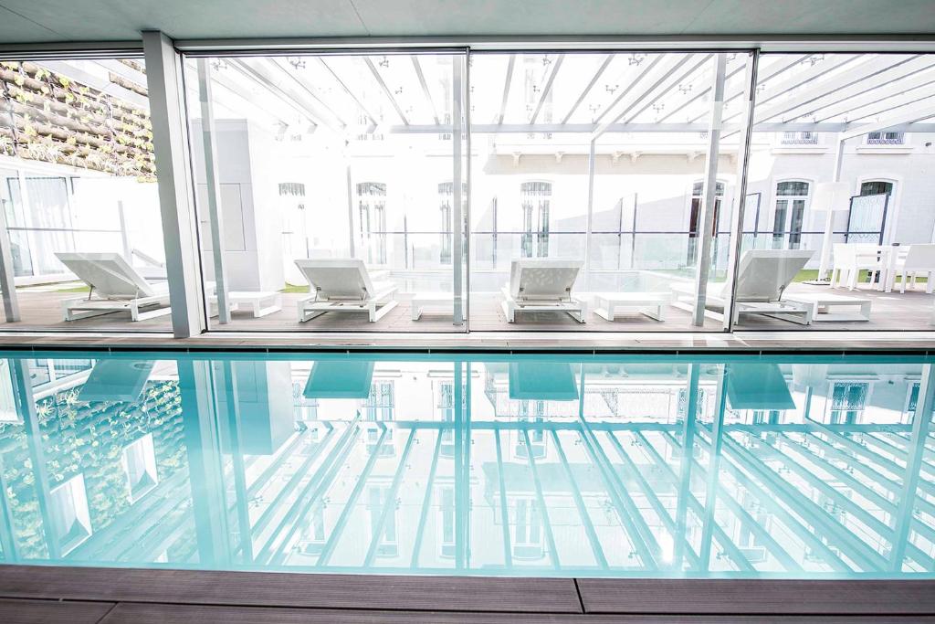 a pool in a building with chairs and a table at BessaHotel Liberdade in Lisbon