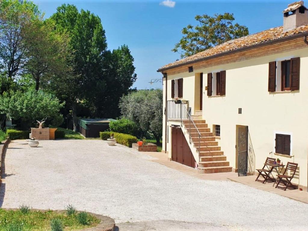 uma casa branca com um pátio e uma entrada em Belvilla by OYO Casale degli Ulivi em Filottrano