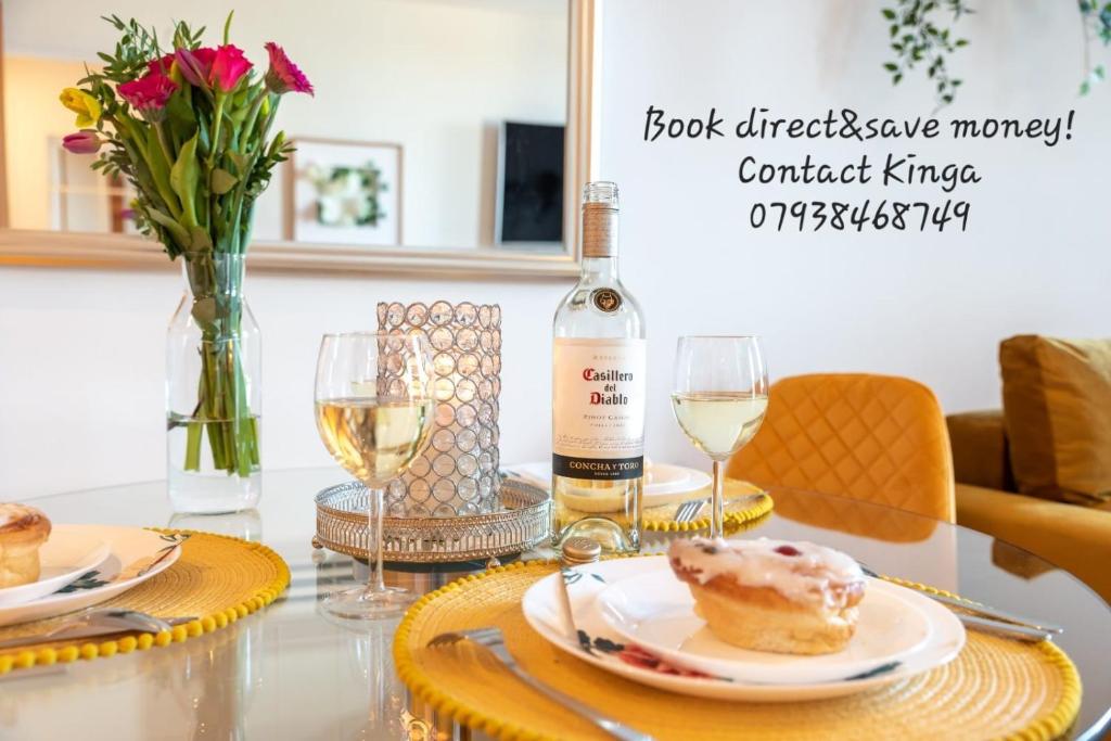 una mesa con dos platos de comida y una botella de vino en Amber Apartment Oasis - Your Gateway to Southampton's Vibrant Heart, Port, Shopping en Southampton