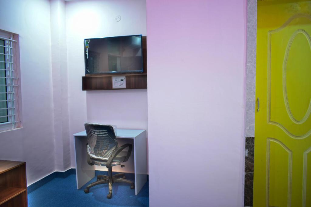 a room with a chair and a desk and a tv at B R Inn in Bengaluru