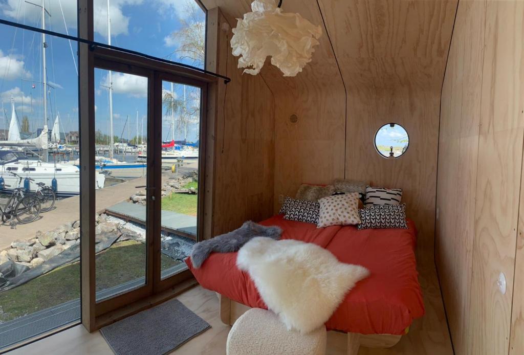 a bedroom with a red bed with a view of a marina at Wikkelhuis 12 in Stavoren