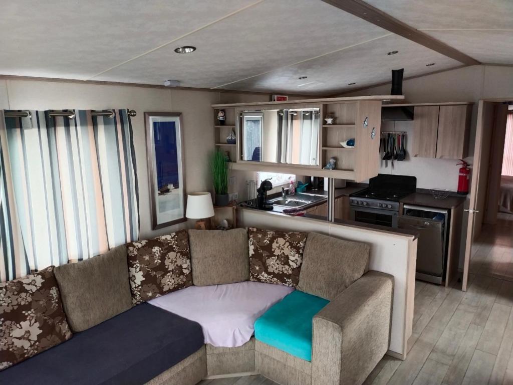 a living room with a couch and a kitchen at MOBIL HOME LE MAGNIFIQUE VALRAS PLAGE in Valras-Plage