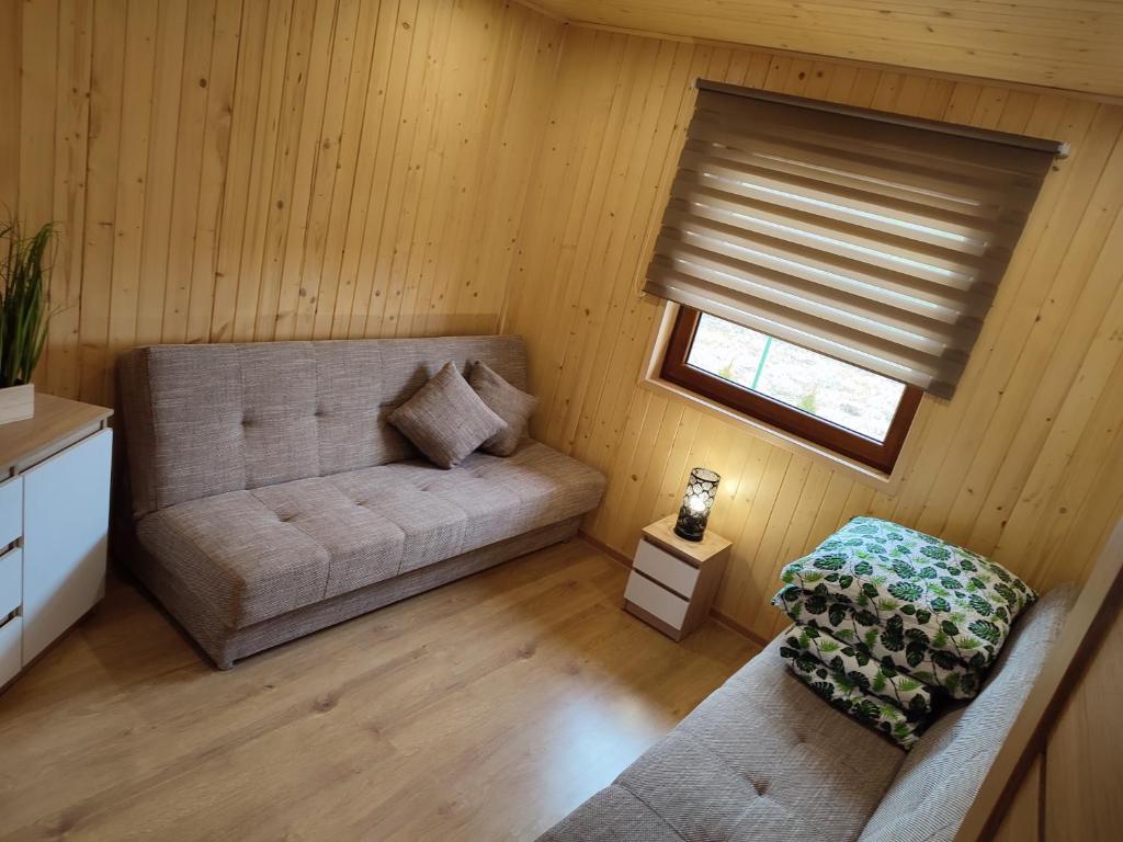 uma sala de estar com um sofá e uma janela em Nocowanie Olga i Oliwia em Okuninka