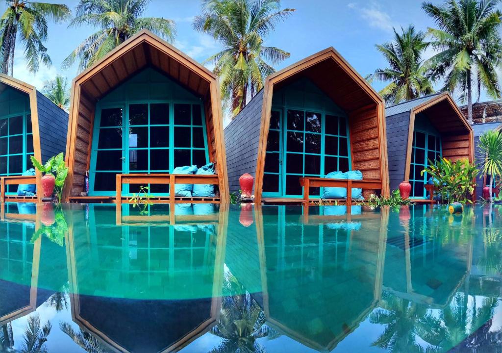 um resort com piscina e palmeiras ao fundo em Absolute Villa em Gili Trawangan