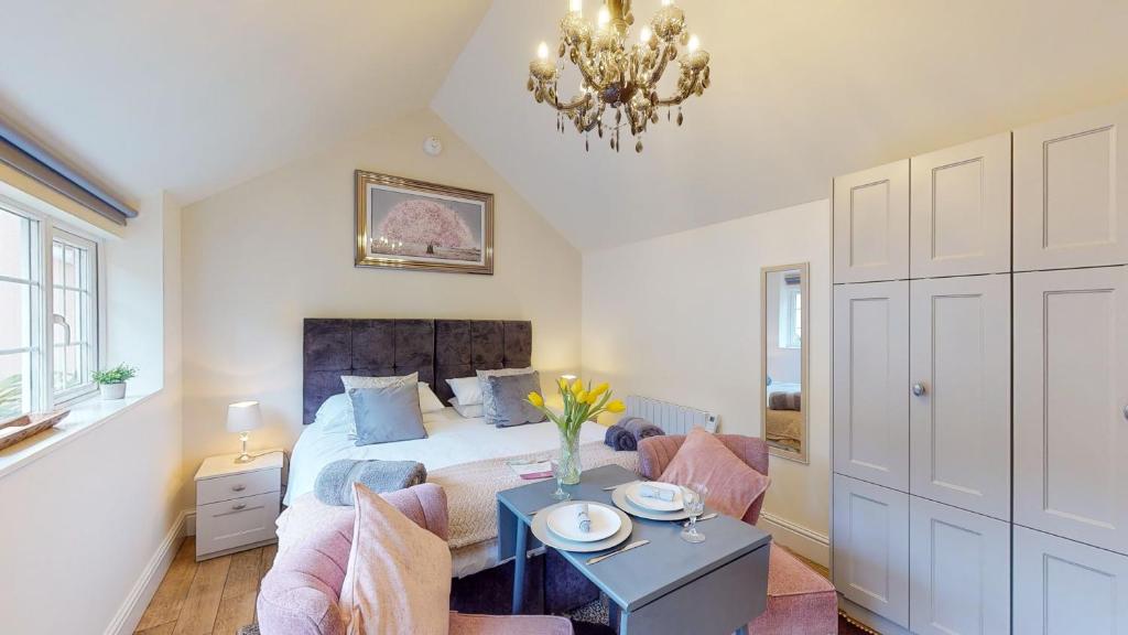 a bedroom with a bed and a table and a chandelier at Hidden Gem Retreat in Budleigh Salterton