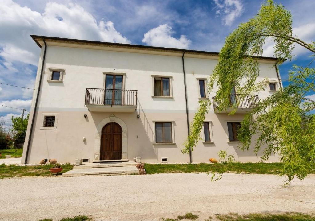 Agriturismo Il Sentiero degli Ulivi - Irpinia في Venticano: منزل أبيض كبير مع شرفة