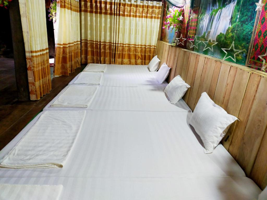 a room with four beds with white sheets and pillows at Minh Khang Homestay - Làng đá cổ Khuổi Ky in Cao Bằng