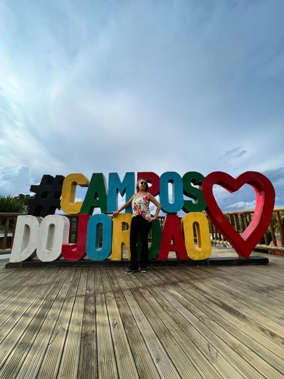 uma mulher em pé em frente a uma placa num passeio marítimo em Seu ap em Campos do Jordão em Campos do Jordão