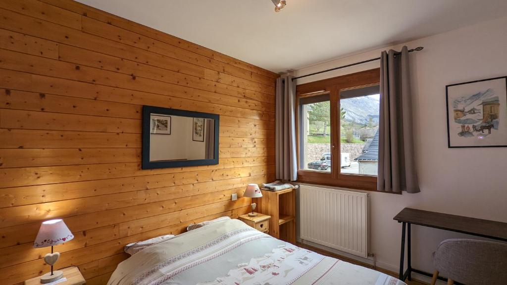 a bedroom with wooden walls and a bed and a window at La Souloise in Le Dévoluy