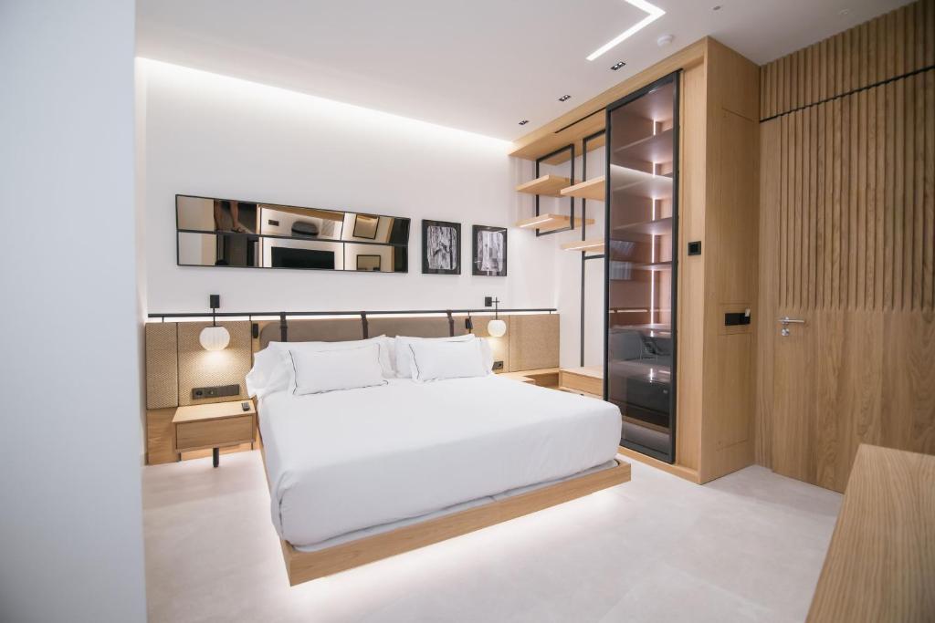 a bedroom with a large white bed and a kitchen at MYR Puerta Serranos in Valencia