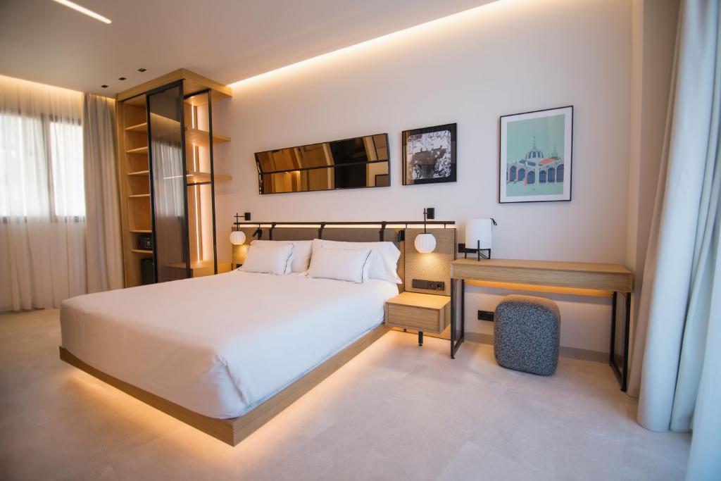 a bedroom with a large white bed and a desk at MYR Puerta Serranos in Valencia