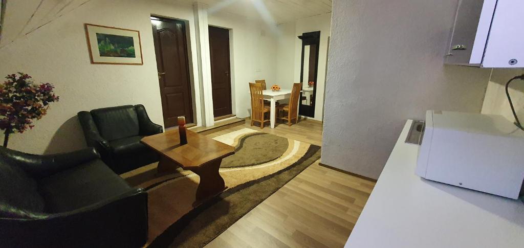 uma sala de estar com uma mesa, um sofá e uma cadeira em Apartman House em Odorheiu Secuiesc