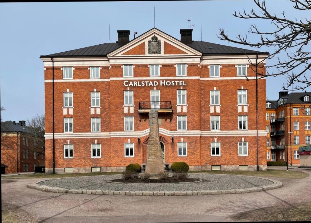 un grand bâtiment en brique rouge avec un panneau. dans l'établissement Carlstad Sport Hostel, à Karlstad