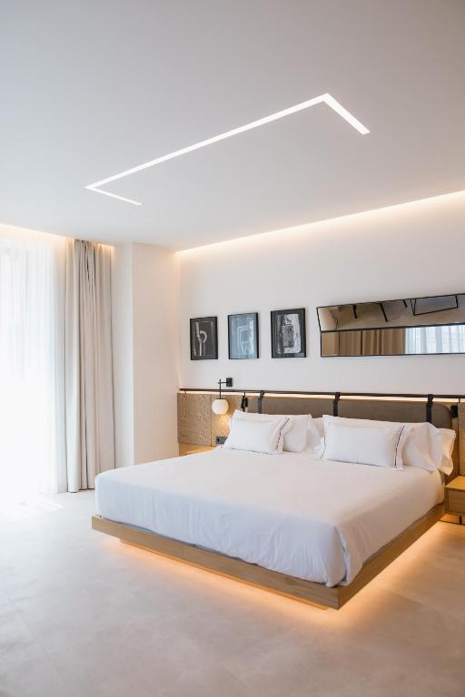 a white bedroom with a large bed with white sheets at MYR Puerta Serranos in Valencia