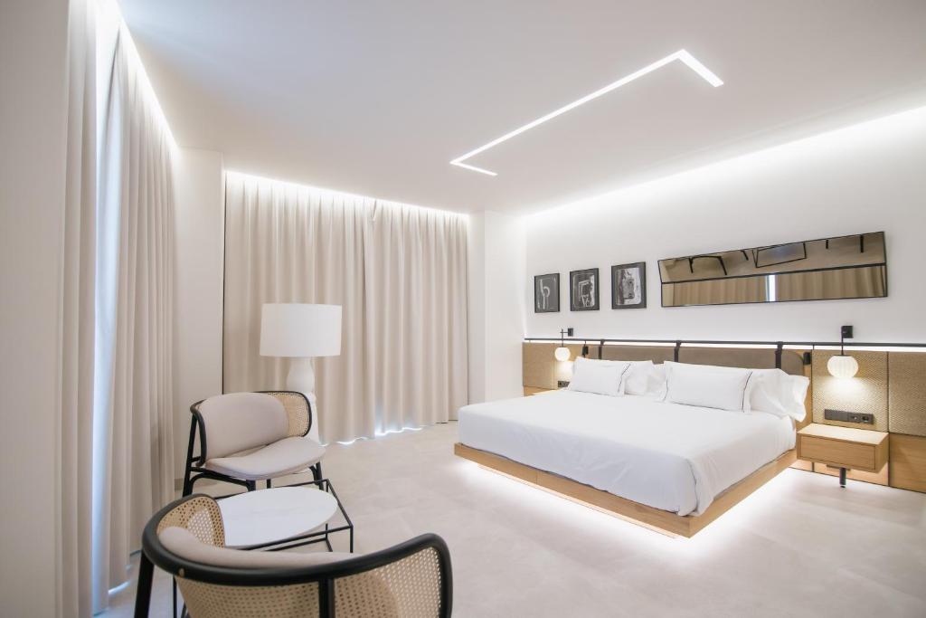 a bedroom with a white bed and two chairs at MYR Puerta Serranos in Valencia