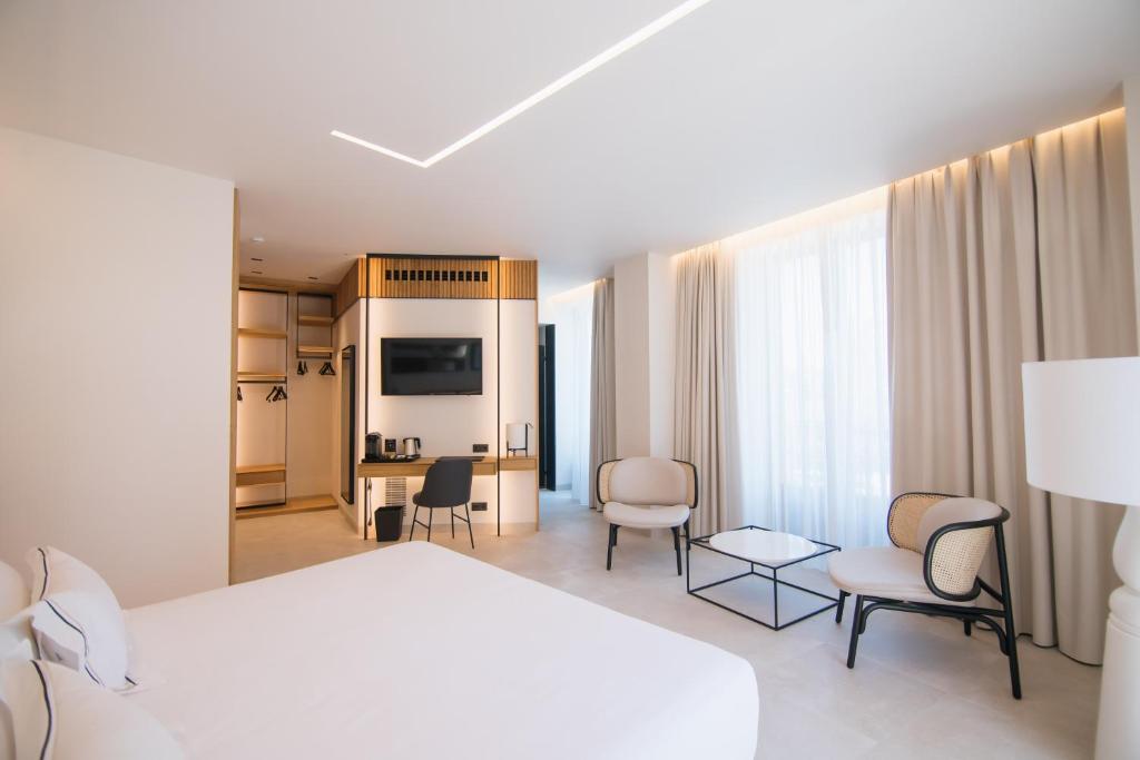 a hotel room with a white bed and a desk and chairs at MYR Puerta Serranos in Valencia