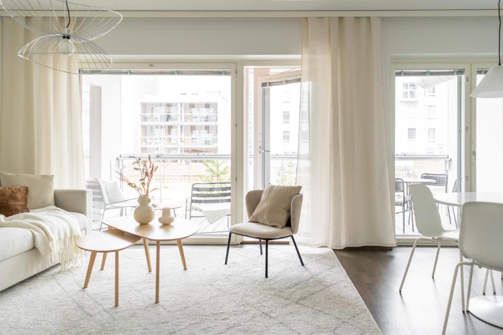 een woonkamer met een bank en een tafel en stoelen bij Iso aurinkoinen parveke ja hyvät yhteydet in Helsinki