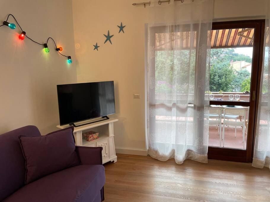 sala de estar con sofá, TV y ventana en Casa di Frilli - a due passi dal mare, en Porto Santo Stefano