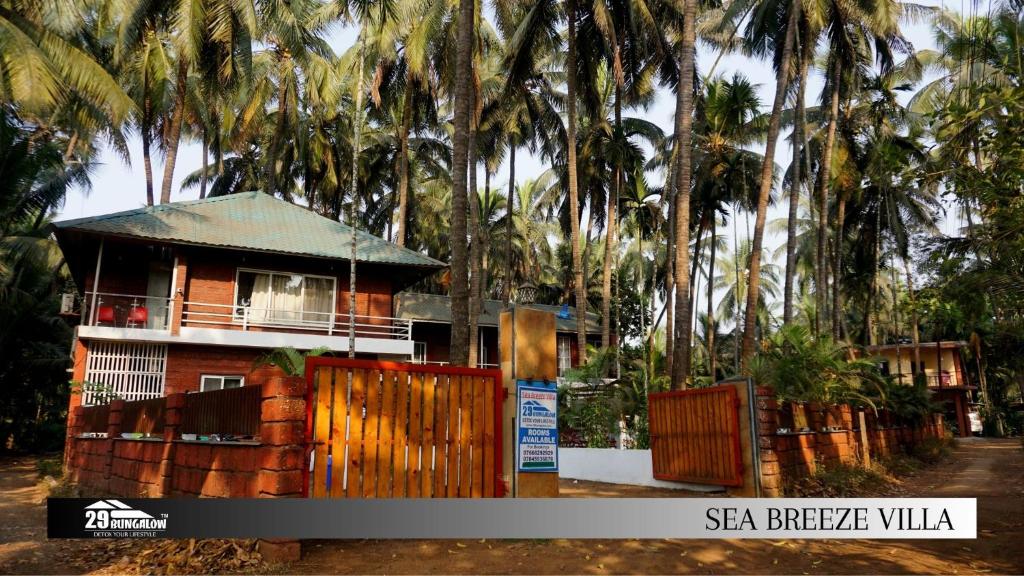 a house with a fence and palm trees at Sea breeze Private Pool Villa - alibaug by 29 Bungalow in Nagaon