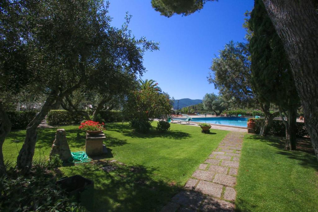 einen Garten mit einem Pool, Bäumen und einem Weg in der Unterkunft Appartamento Maria Teresa in Porto Santo Stefano