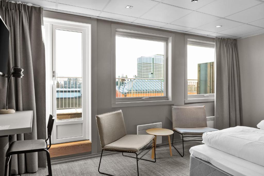 a hotel room with a bed and chairs and windows at Comfort Hotel Børsparken in Oslo